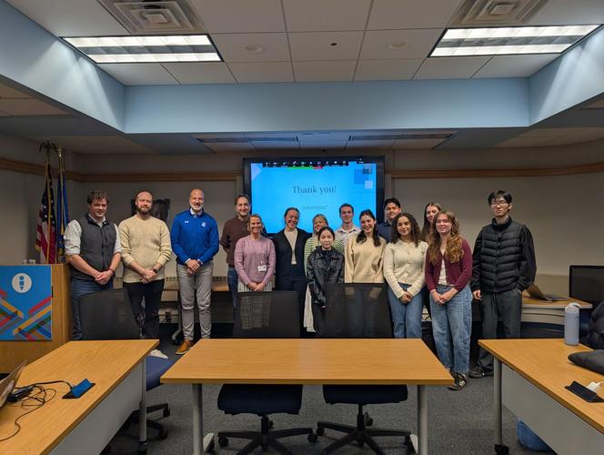 School district leaders and sociology students standing in front of a projector screen.
