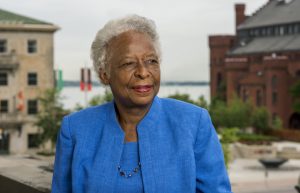 Photo of a woman in a blue blazer standing in front of buildings
